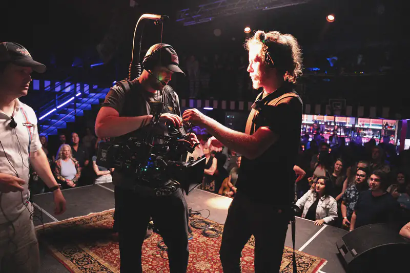 A camera operator and director setting up a shot on a live venue stage.